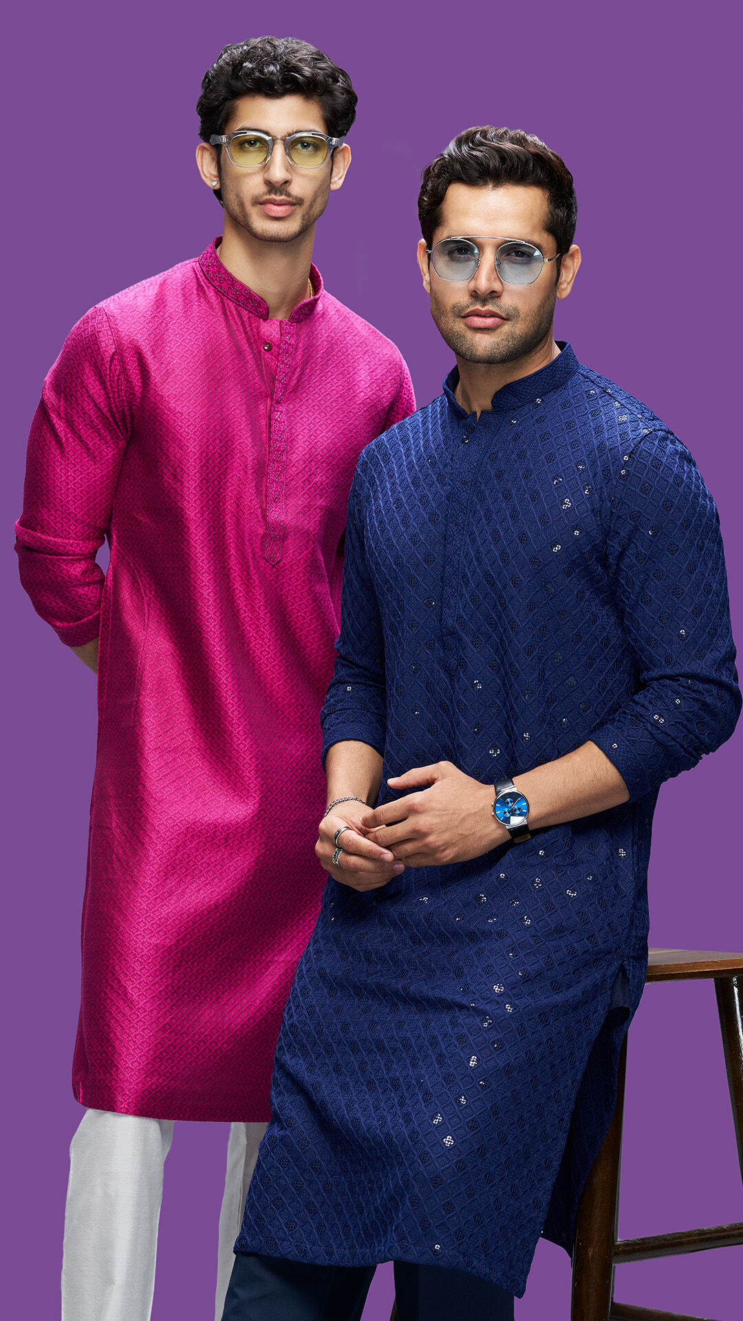 Two young men wearing festive kurtas in magenta and navy blue, styled for a traditional celebration.